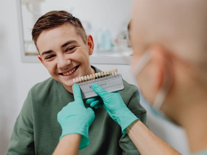 Dentist shade-matching veneers for a smiling patient